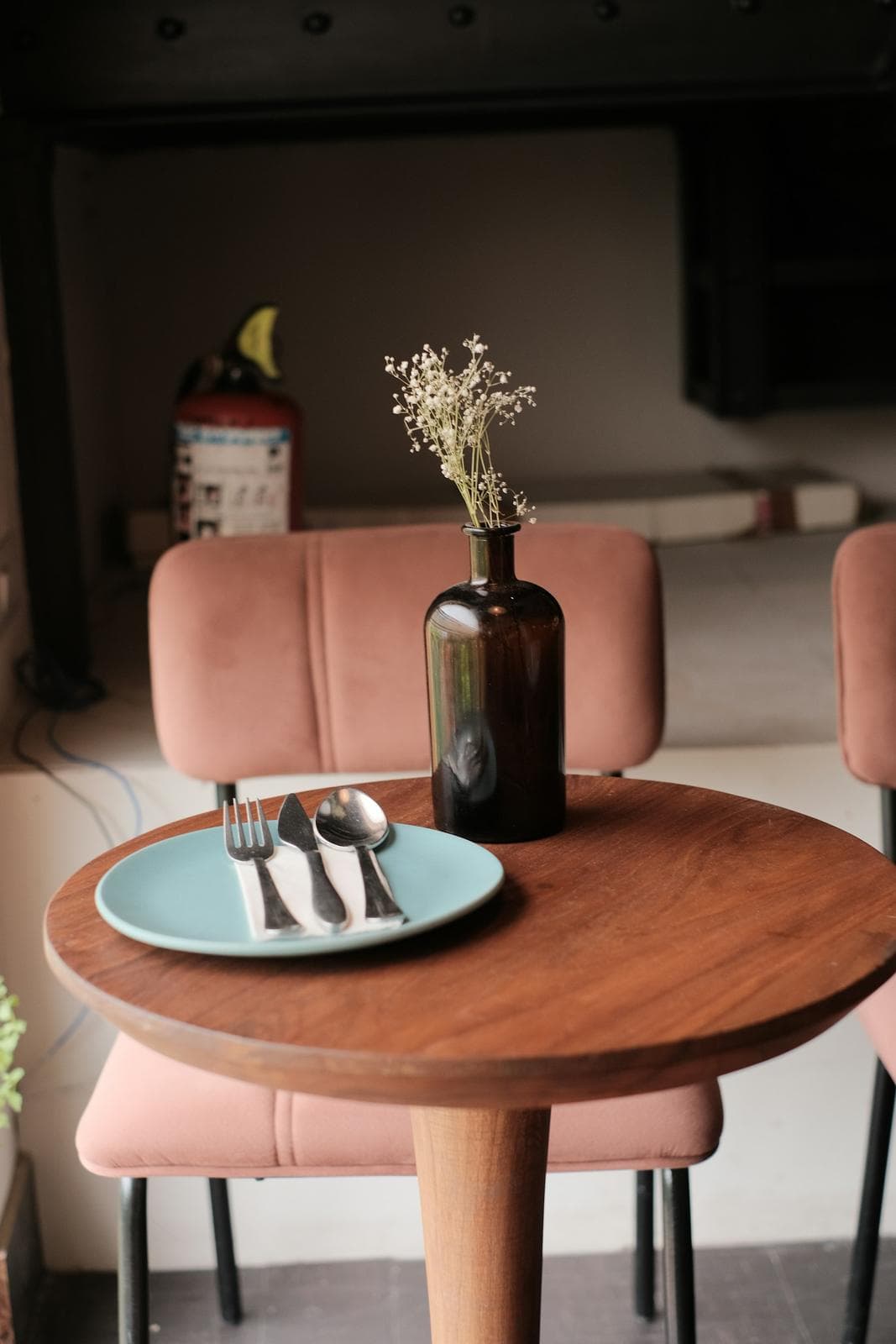Round café table with a vase of flowers and pink chairs
