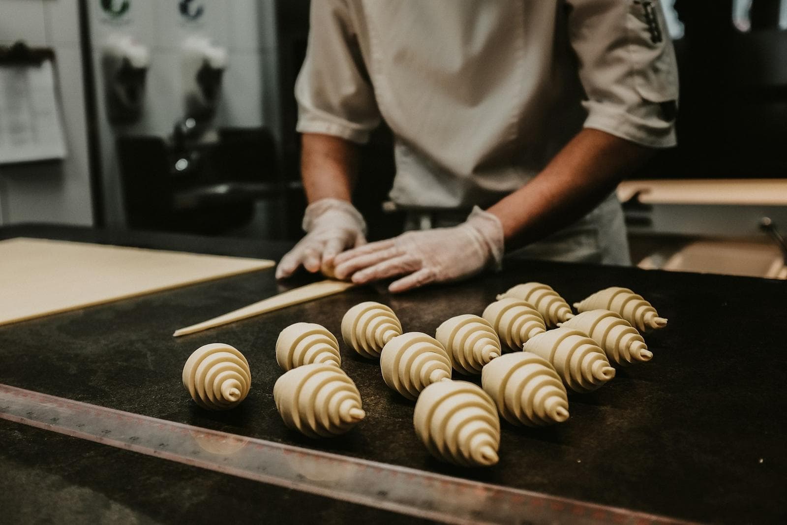 Baker shaping croissant dough on a floured counter
