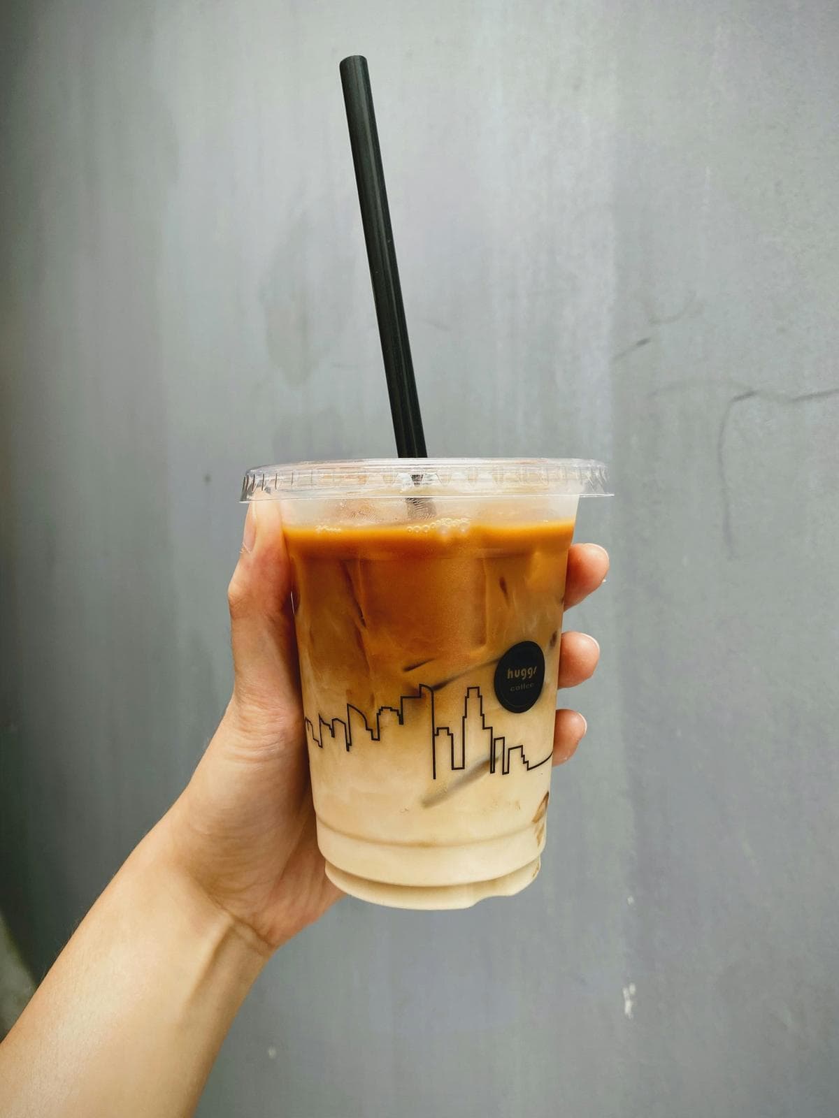 Hand holding an iced latte in a takeaway cup