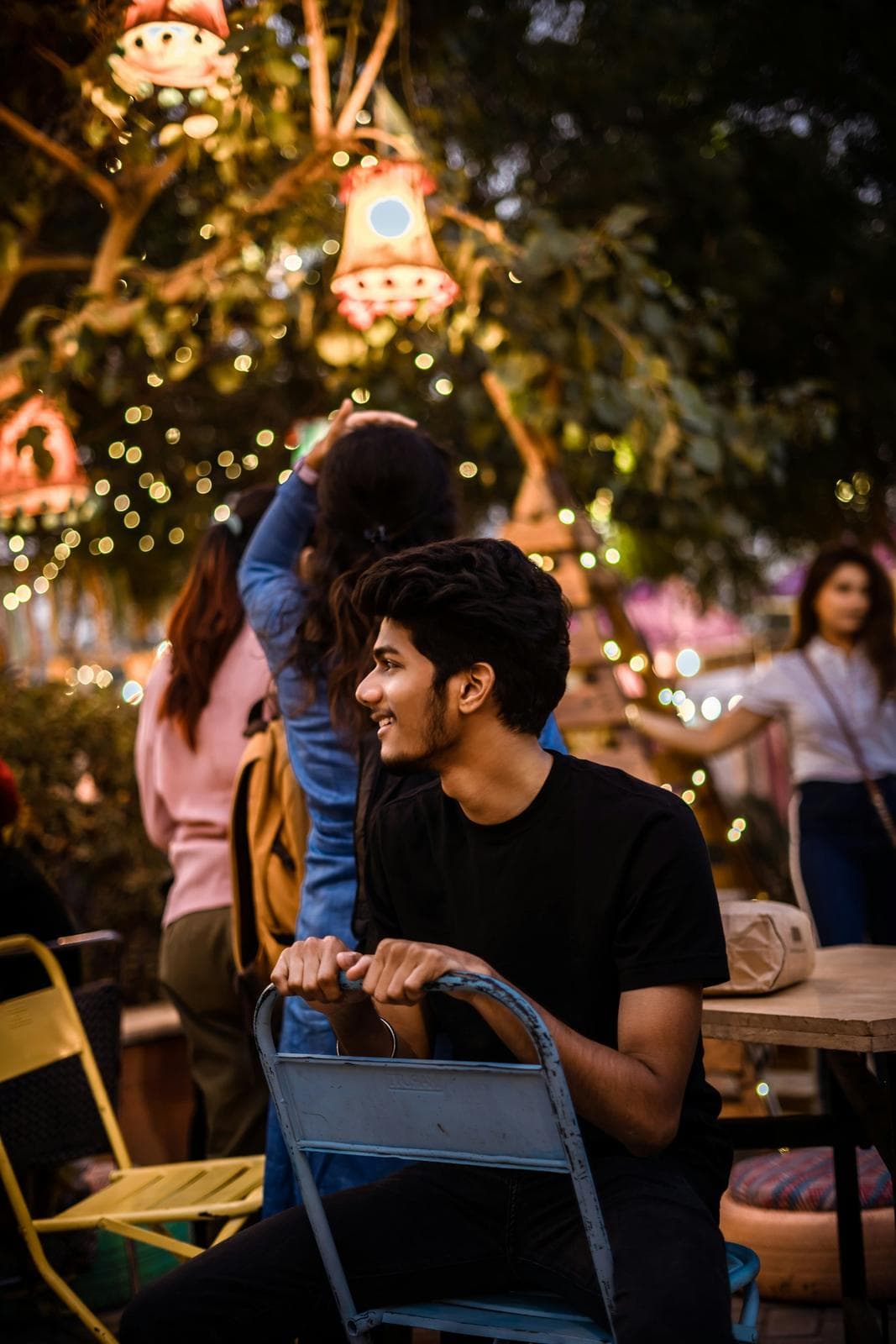 Friends hanging out at a café table under fairy lights