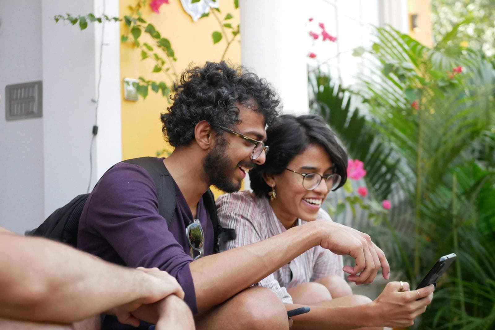 Two friends laughing at something on a phone at a café table