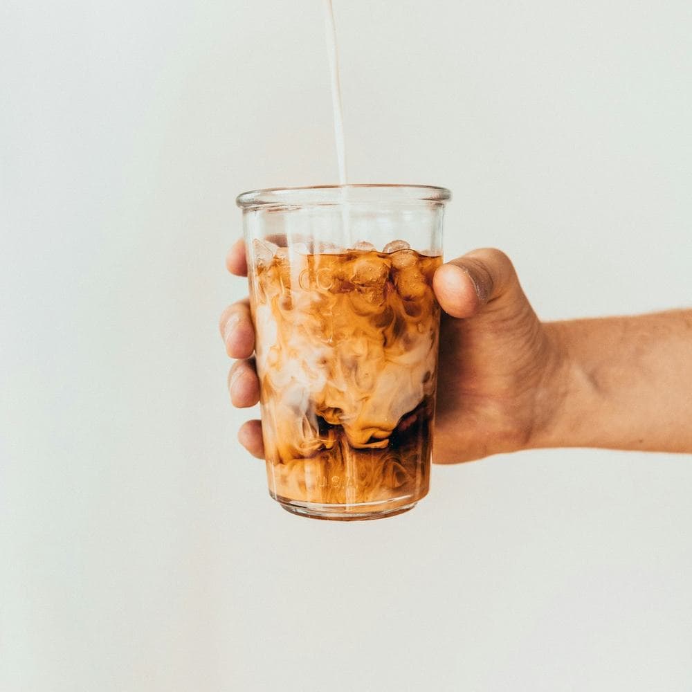 Iced Spanish latte with milk swirling through coffee