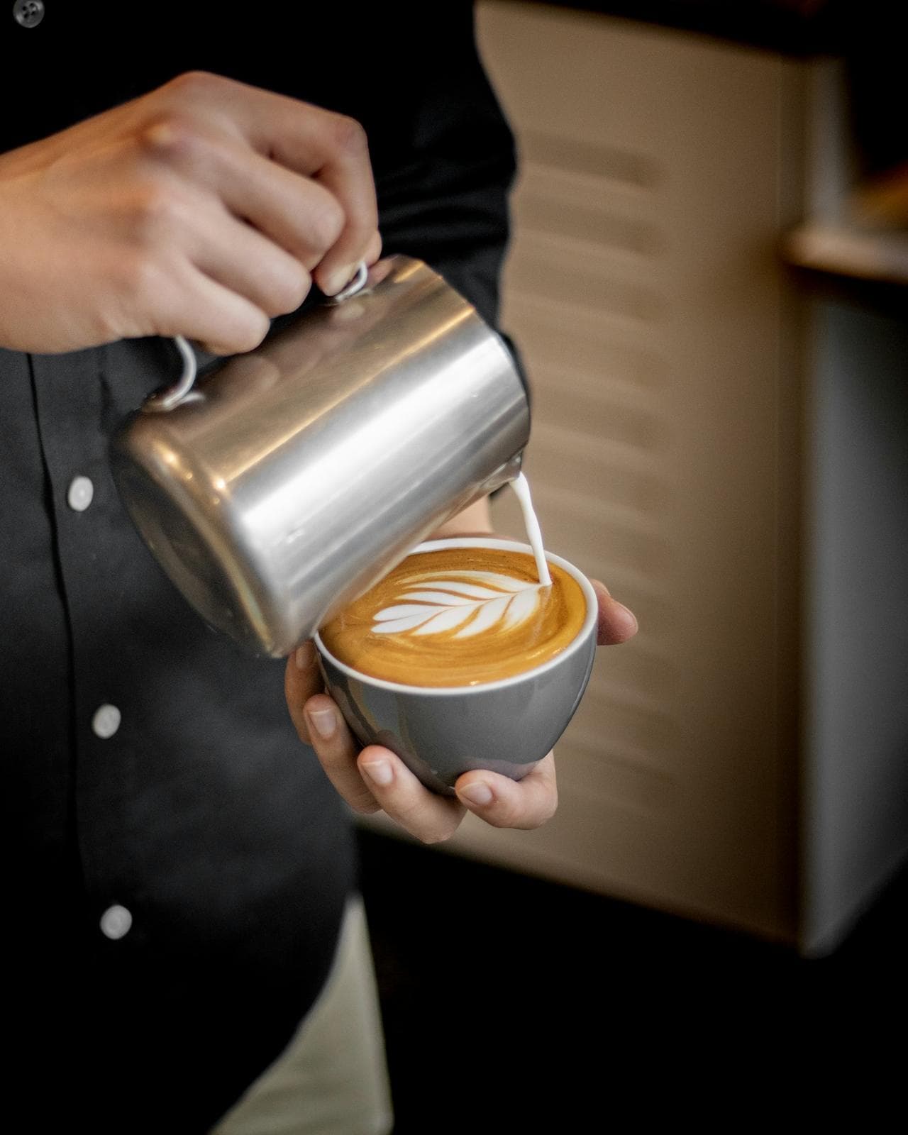 Barista finishing a tulip of latte art in a ceramic cup