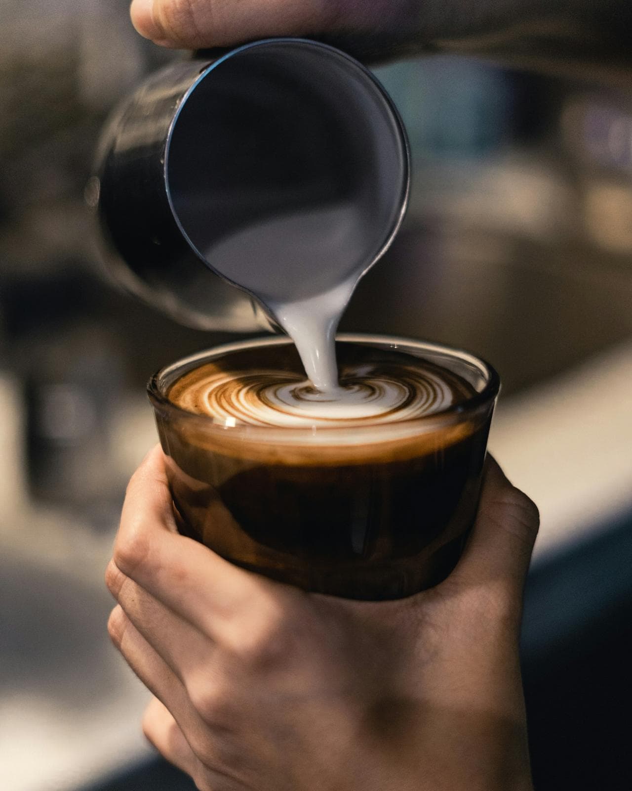 Barista pouring steamed milk into an espresso to make latte art