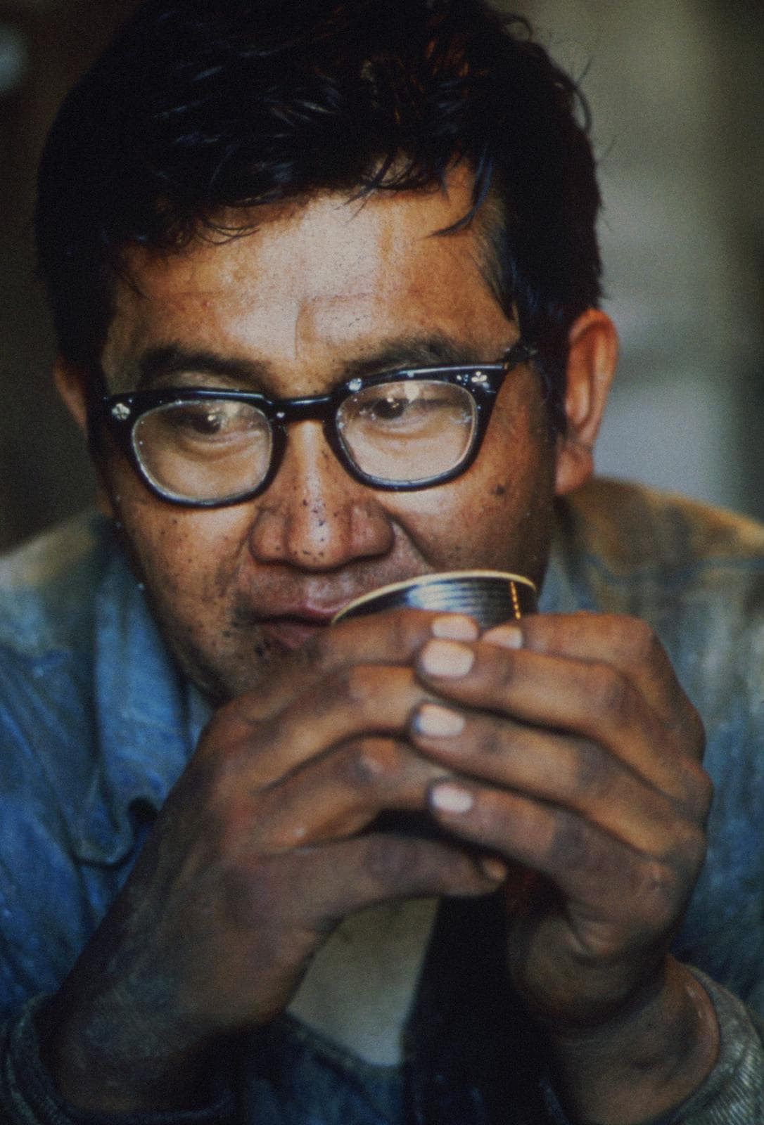 Man in glasses sipping from a cup with both hands