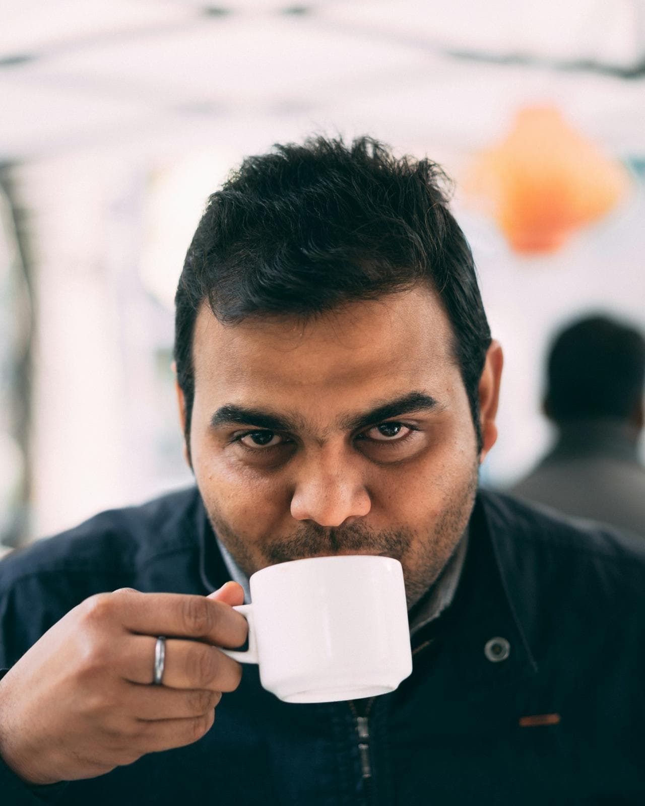 Man taking a sip from a white coffee cup